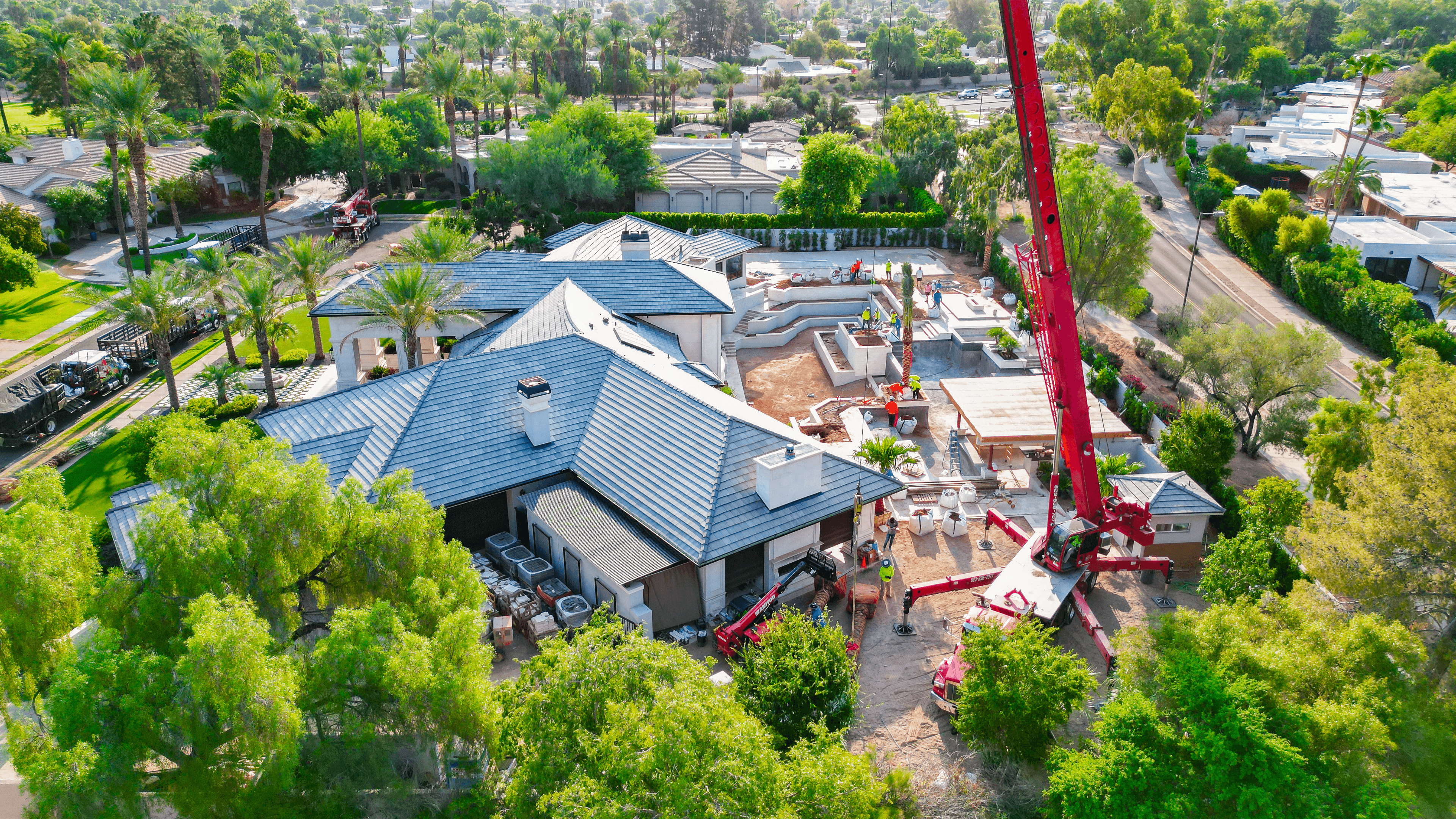 Large crane planting trees in a luxury backyard.